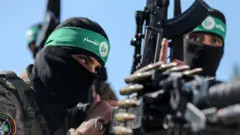 Getty Images Hamas fighters wearing balaclavas hold weapons