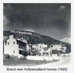 Houses sit at the base of a hill with the Hollywoodland sign visible above, in black and white, showcasing the early development and the sign's prominent placement.
