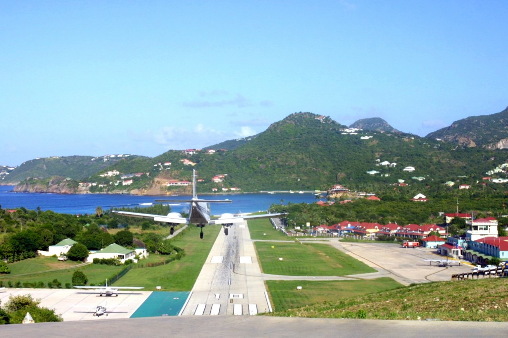 Image of a small airplane landing at St. Barth Airport with a beach in the background