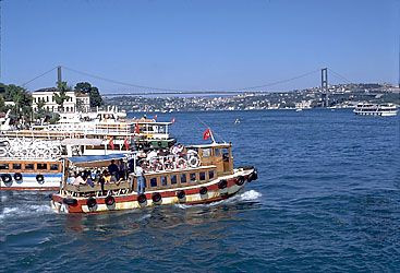 Boğazici Bridge in Istanbul, Turkey, with ferries in the foreground, highlighting transportation across the Bosporus.
