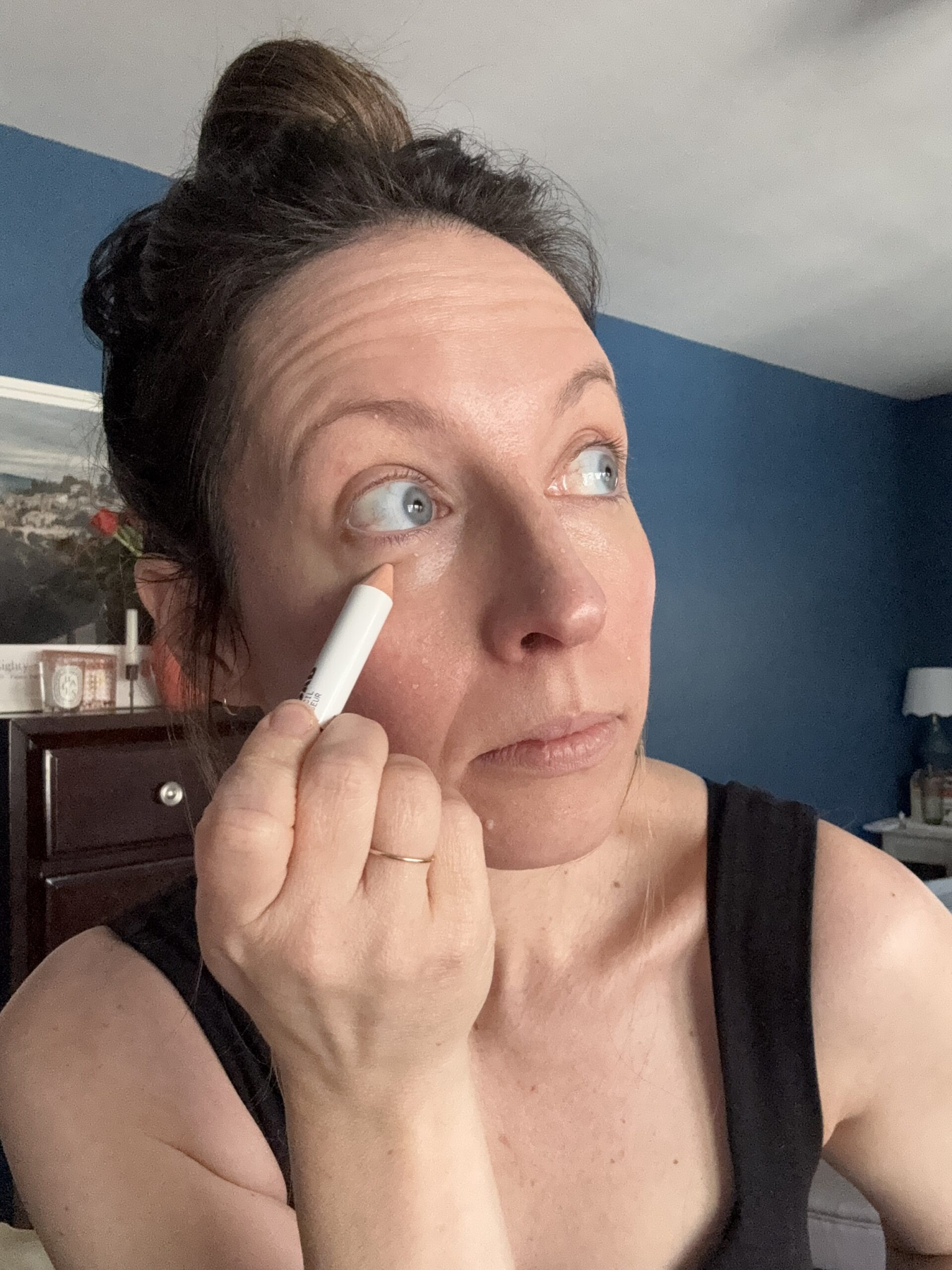 Applying concealer under eye with pencil