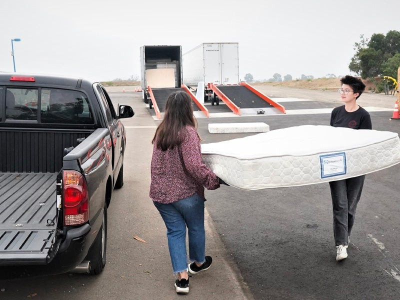 Two people unloading mattress for recycling