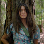 Daisy Edgar-Jones as Kya in Where the Crawdads Sing film, looking thoughtfully into the marsh.