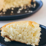 Close up of vanilla yellow cake on navy plate.