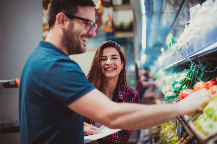 Couple consulting a shopping list in a grocery store.