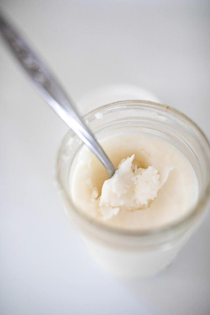 storing rendered beef fat in glass mason jars with white lids on an antique stove