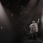 Jelly Roll performing his song Save Me, his arm outstretched and the mic in his other hand.