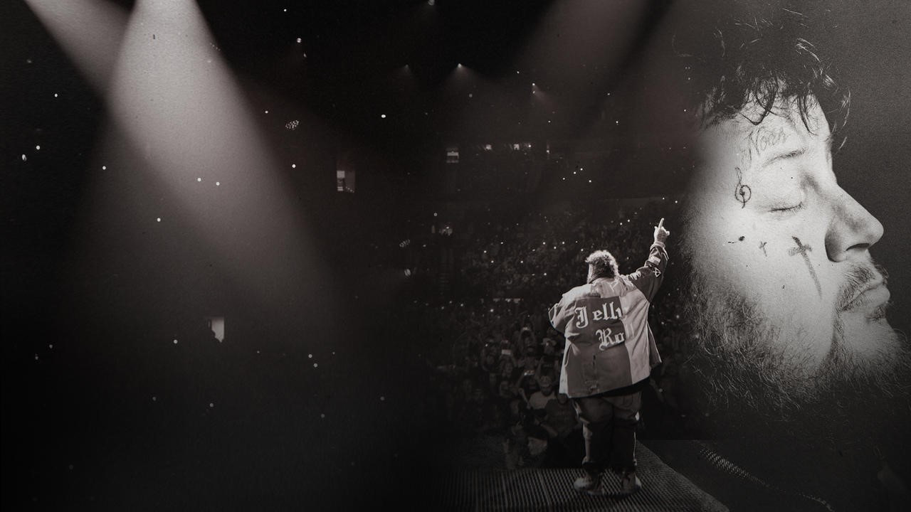 Jelly Roll performing his song Save Me, his arm outstretched and the mic in his other hand.