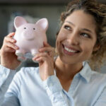 Woman smiling while working on a laptop, representing how to increase income to save money