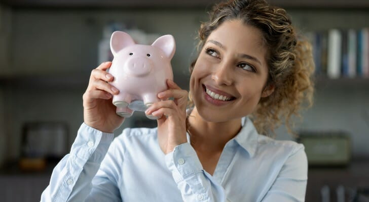 Woman smiling while working on a laptop, representing how to increase income to save money