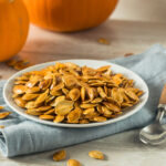 Roasted pumpkin seeds on a plate with a spoon